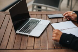 Professional working on a laptop and taking notes at a desk.