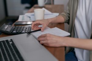 Person comparing debt mediation companies on a laptop with a notepad of questions